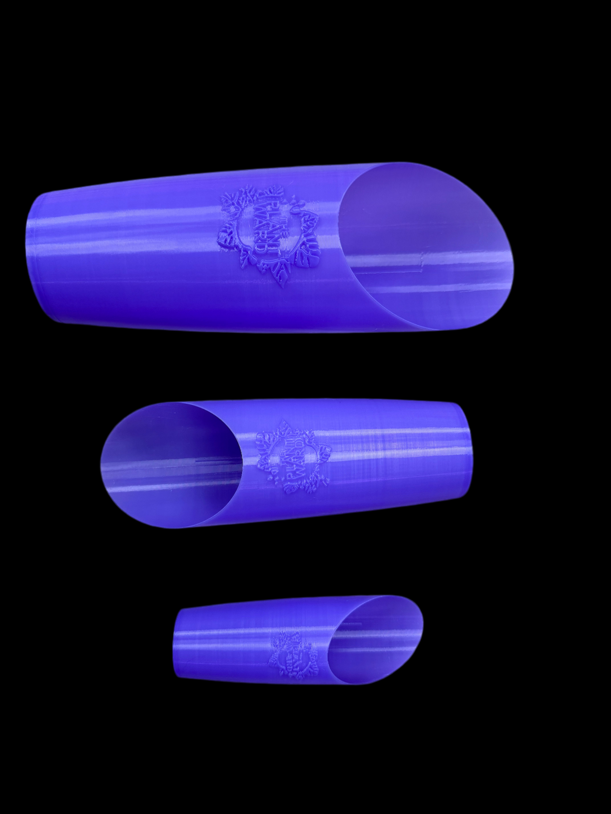 Is a photo of three periwinkle plastic soil scoops featuring the plant ward logo on front arranged smallest to largest bottom up in an alternating pattern against a black background. 